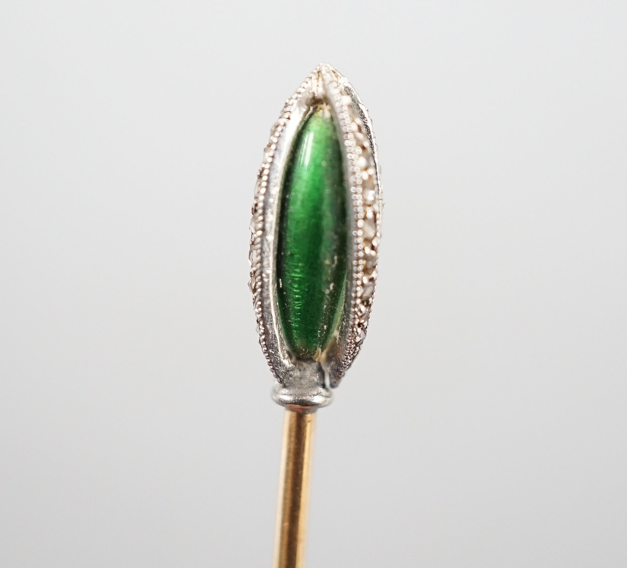 An early 20th century yellow metal stick pin, with rose cut diamond and green enamel set terminal, 76mm, gross weight 2.3 grams.